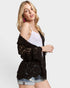 Woman wearing a black lace cardigan over a white top on a white background