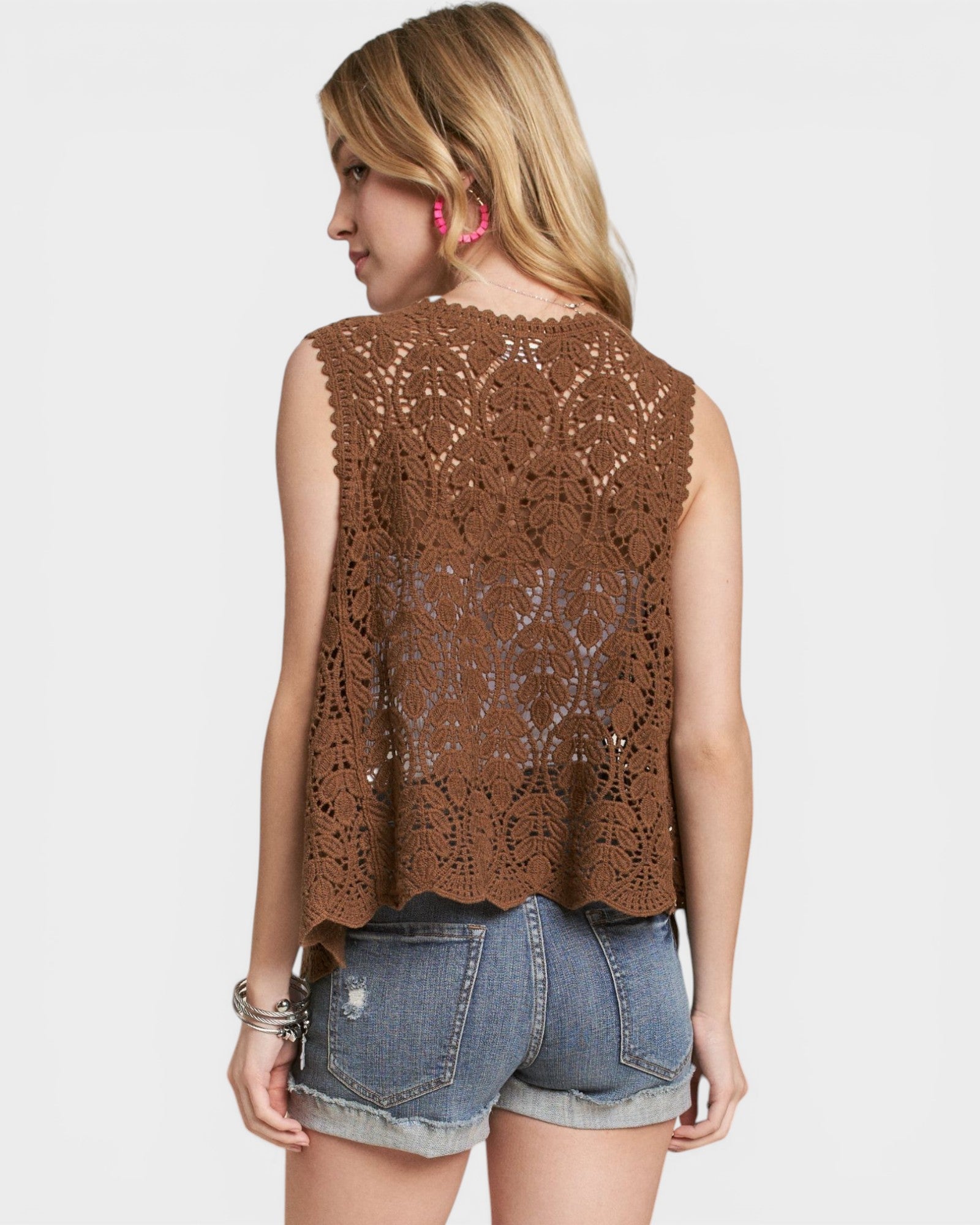 Woman wearing a brown crochet top and denim shorts on a white background