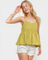 Woman wearing a yellow smocked top and white shorts on a plain background
