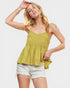 Woman wearing a green top and white shorts on a plain background