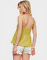 Woman wearing a yellow top and white shorts on a plain background