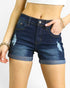 A close-up of a model wearing dark blue distressed denim shorts with rolled hems and light wash frayed details on the sides.