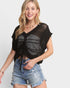 Woman wearing a black crochet top and denim shorts on a white background