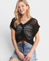 Woman wearing a black crochet top and denim shorts on a white background