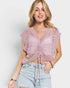 Woman wearing a pink crochet top and light blue jeans on a plain background
