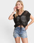 Woman wearing a black crochet top and denim shorts on a white background