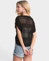 Woman wearing a black crochet top and denim shorts on a white background