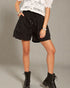 Person wearing black shorts and black boots on a plain background