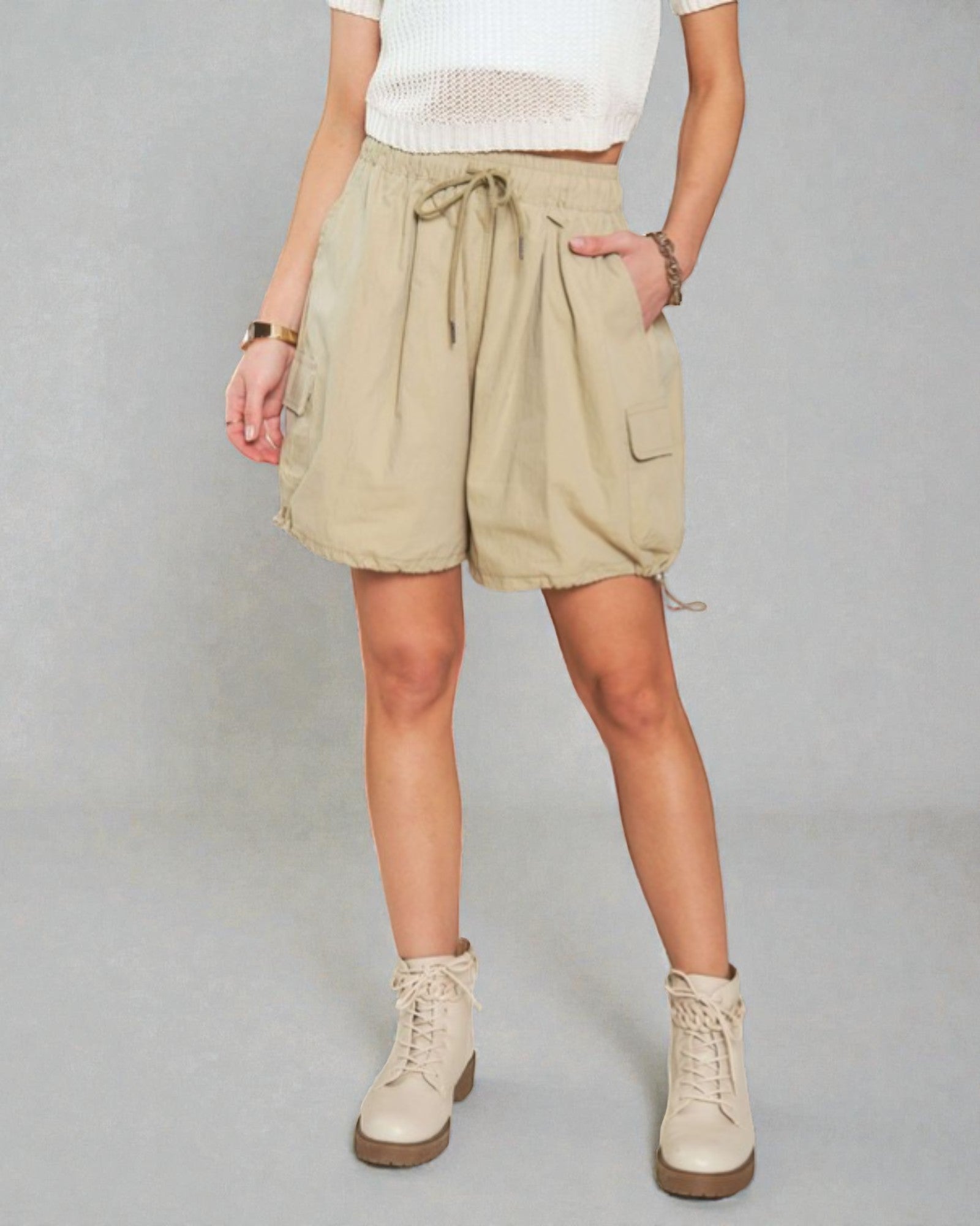 Person wearing beige shorts and boots on a plain background