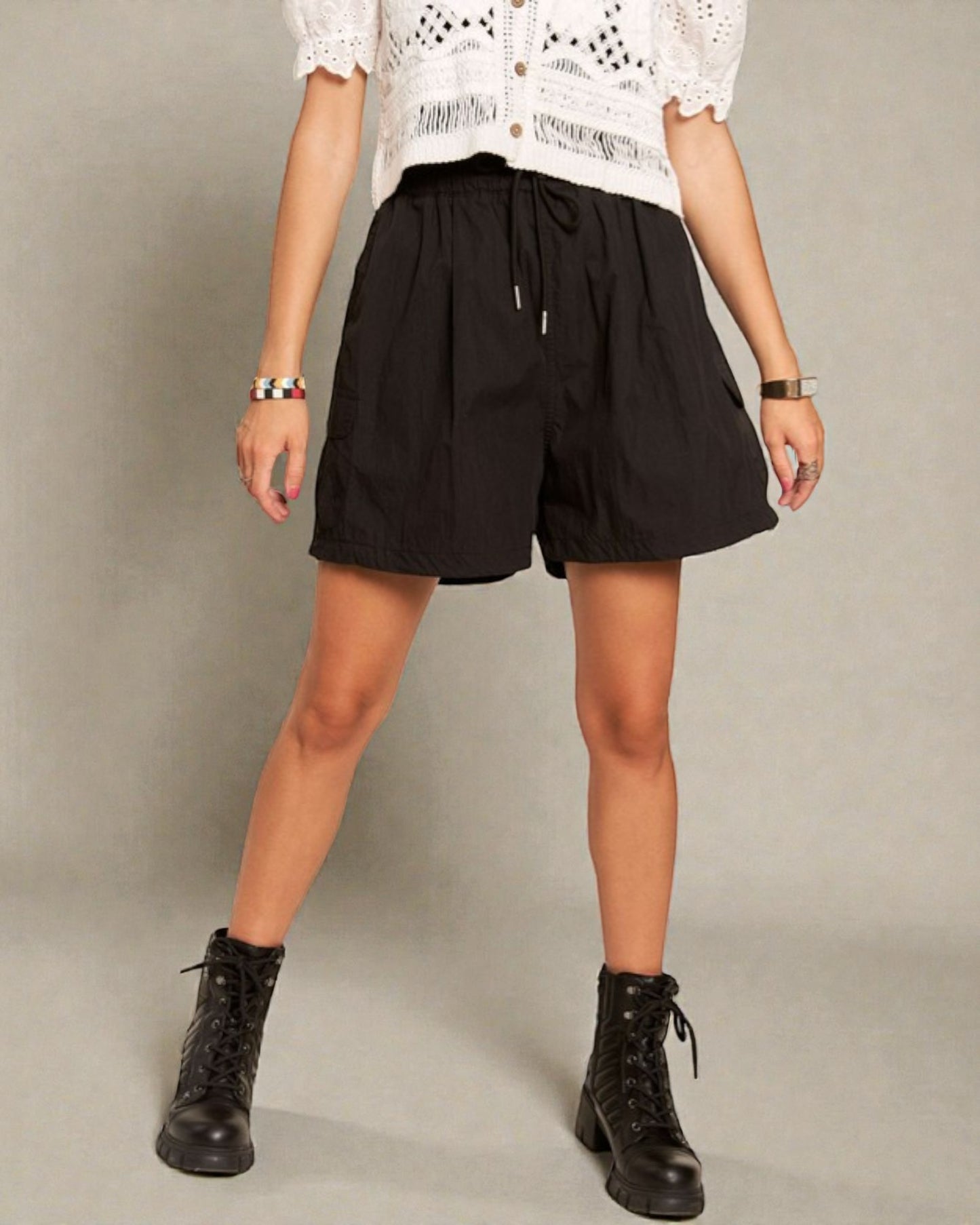 Person wearing black shorts and black boots on a plain background