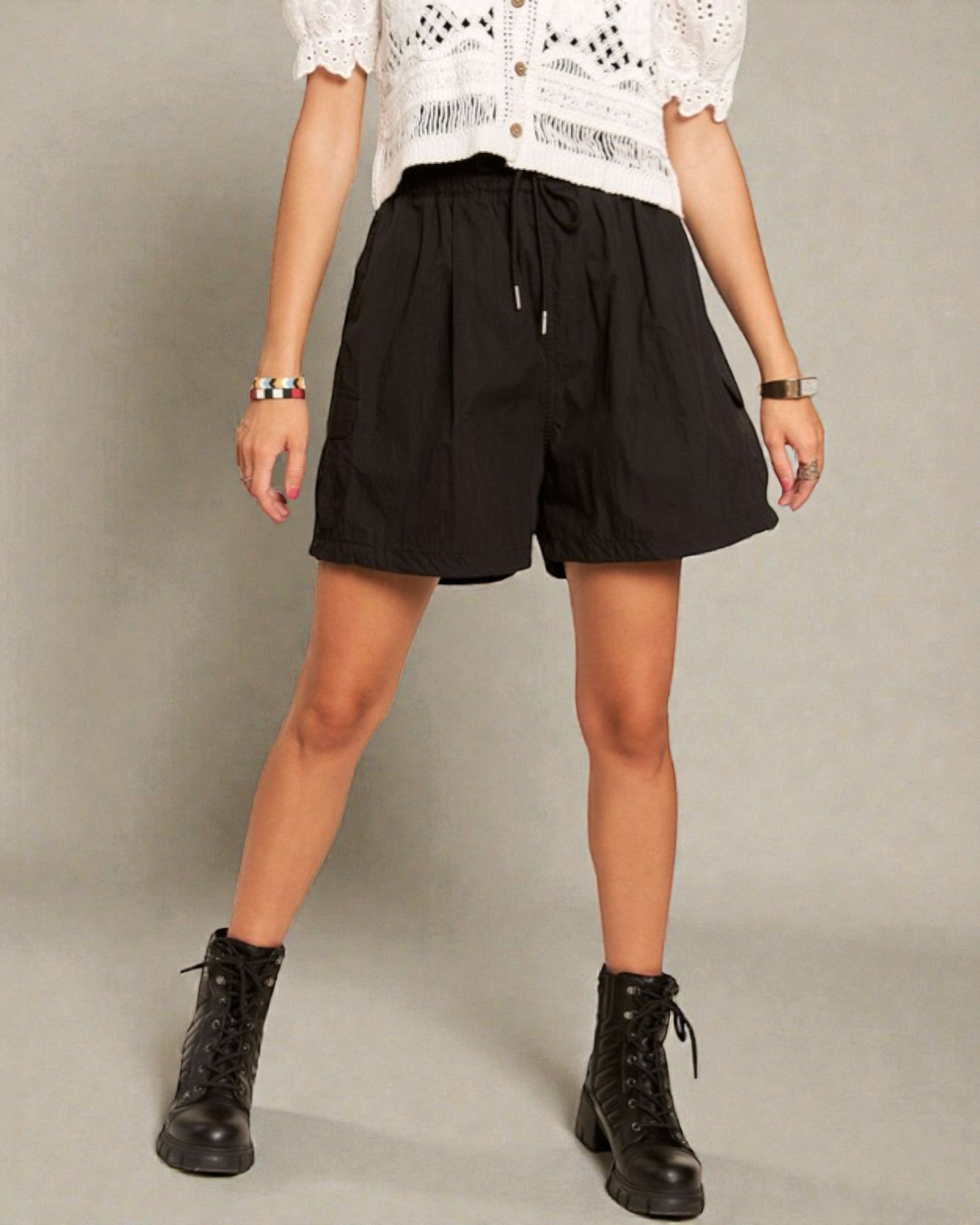 Person wearing black shorts and black boots on a plain background