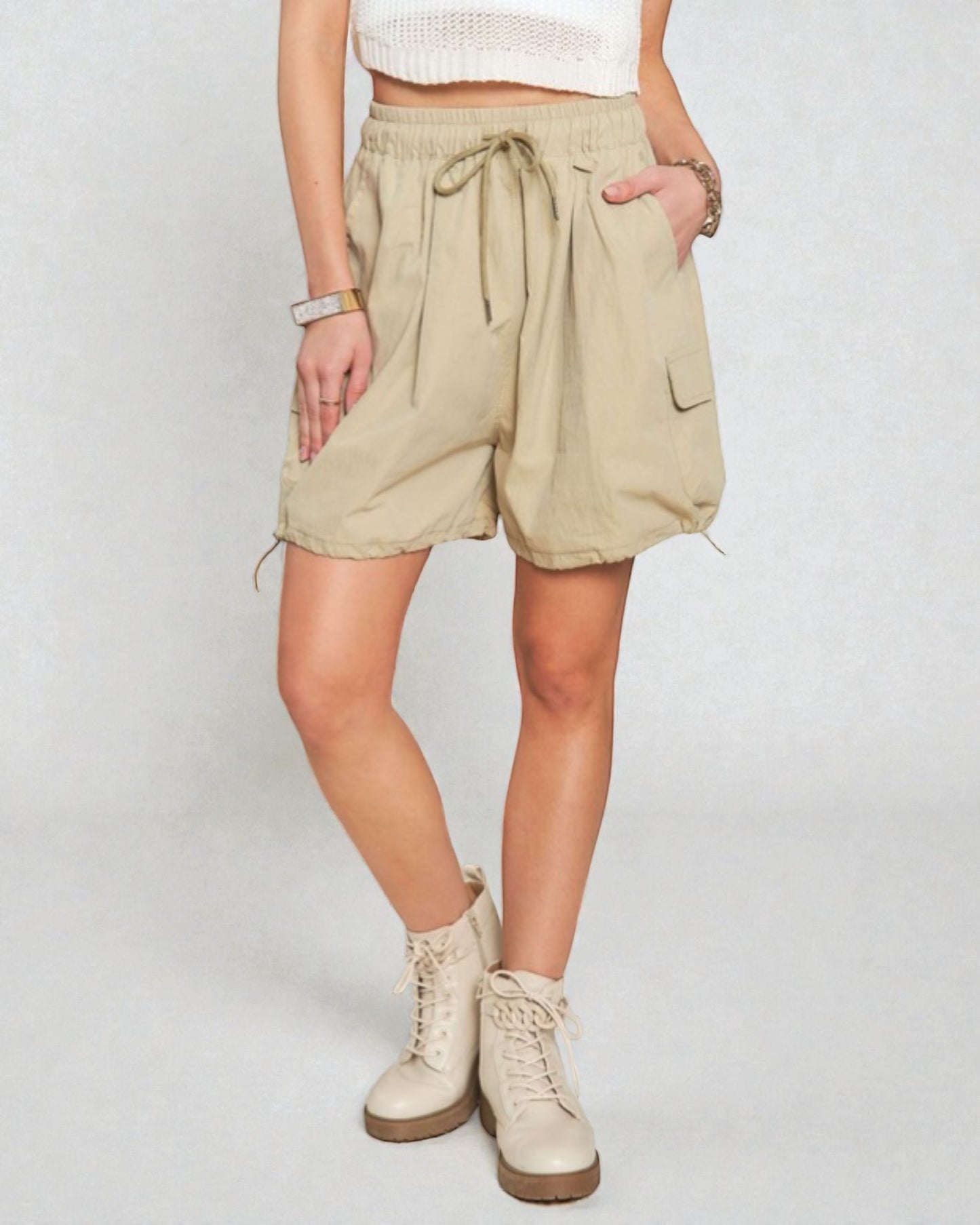 Person wearing beige shorts and white boots on a plain background