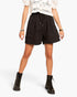 A model wearing black drawstring shorts, a white crochet top, and black lace-up combat boots, photographed against a clean white studio background.
