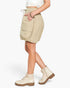 A model wearing beige cargo-style biker shorts with a drawstring waist, side pockets, and a gathered elastic hem, styled with cream combat boots against a plain white background.