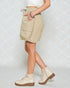 Person wearing beige cargo shorts and white boots on a light background