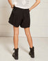 Person wearing black shorts and black boots on a white background
