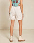 Person wearing a colorful crochet top, white shorts, and beige boots on a neutral background