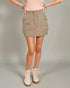 Person wearing a beige skirt and boots on a plain background