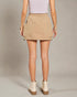 Person wearing a beige skirt and white boots on a plain background