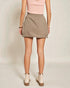 Person wearing a beige skirt and pink top on a plain background