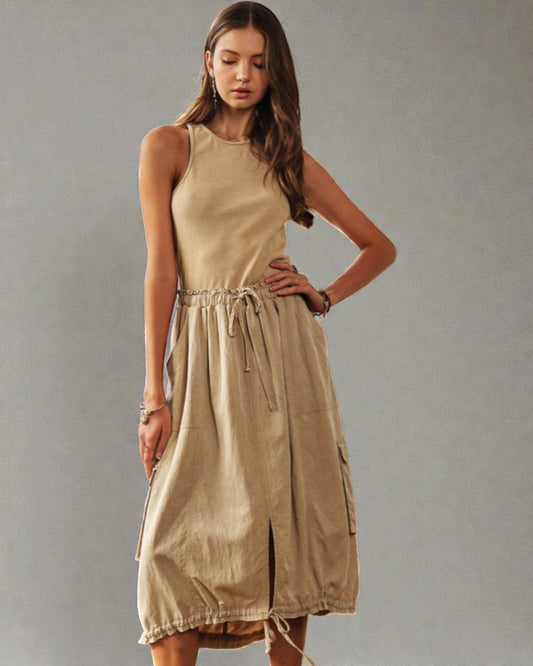 Woman wearing a beige sleeveless dress against a plain background