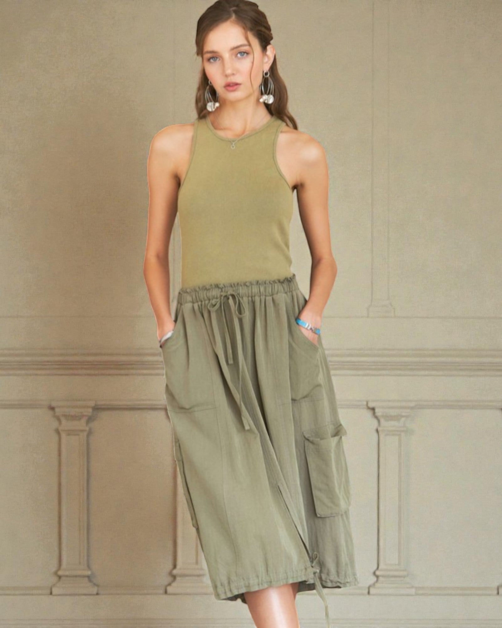 Woman wearing a green sleeveless dress against a beige wall.