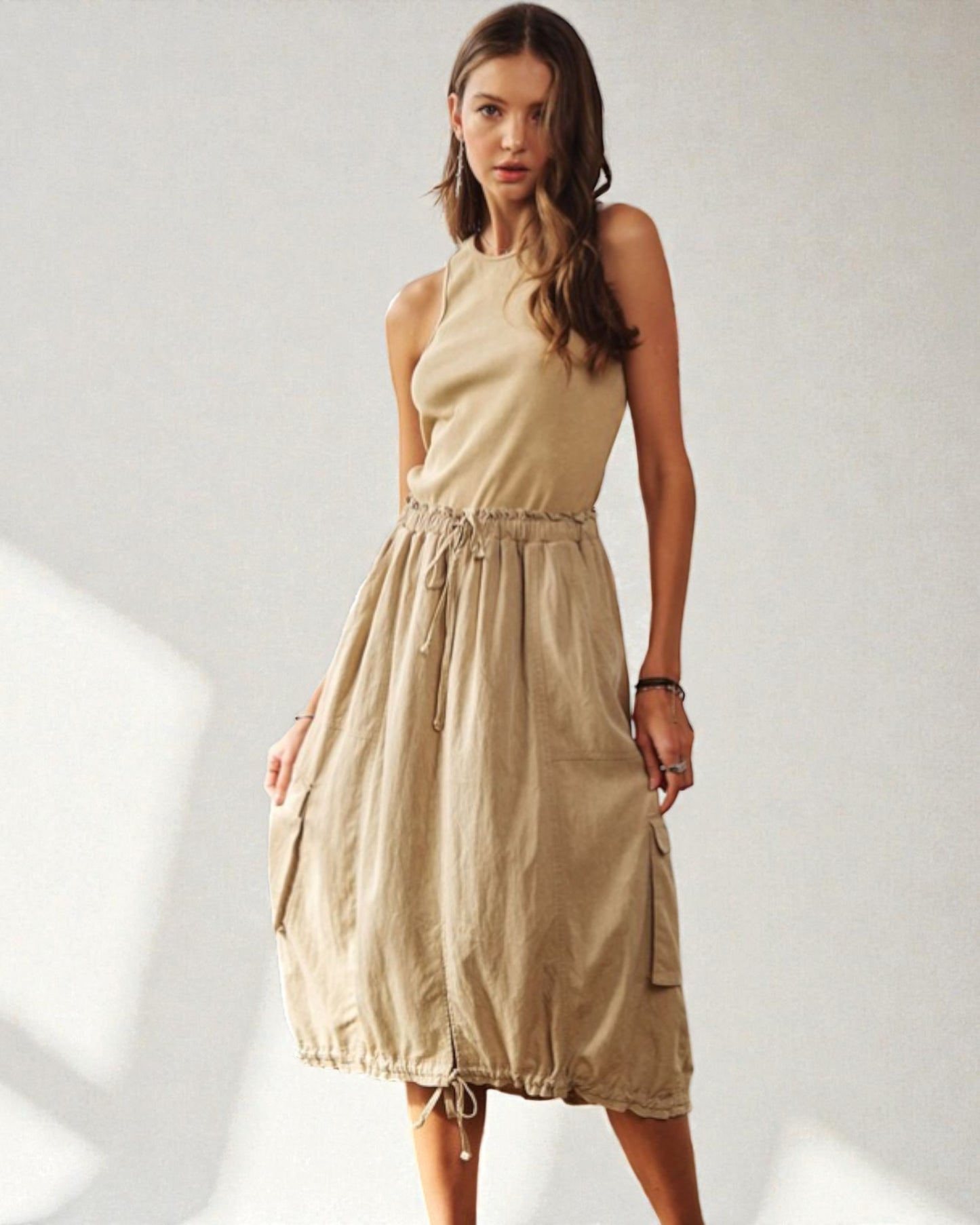 Woman wearing a beige sleeveless dress on a white background