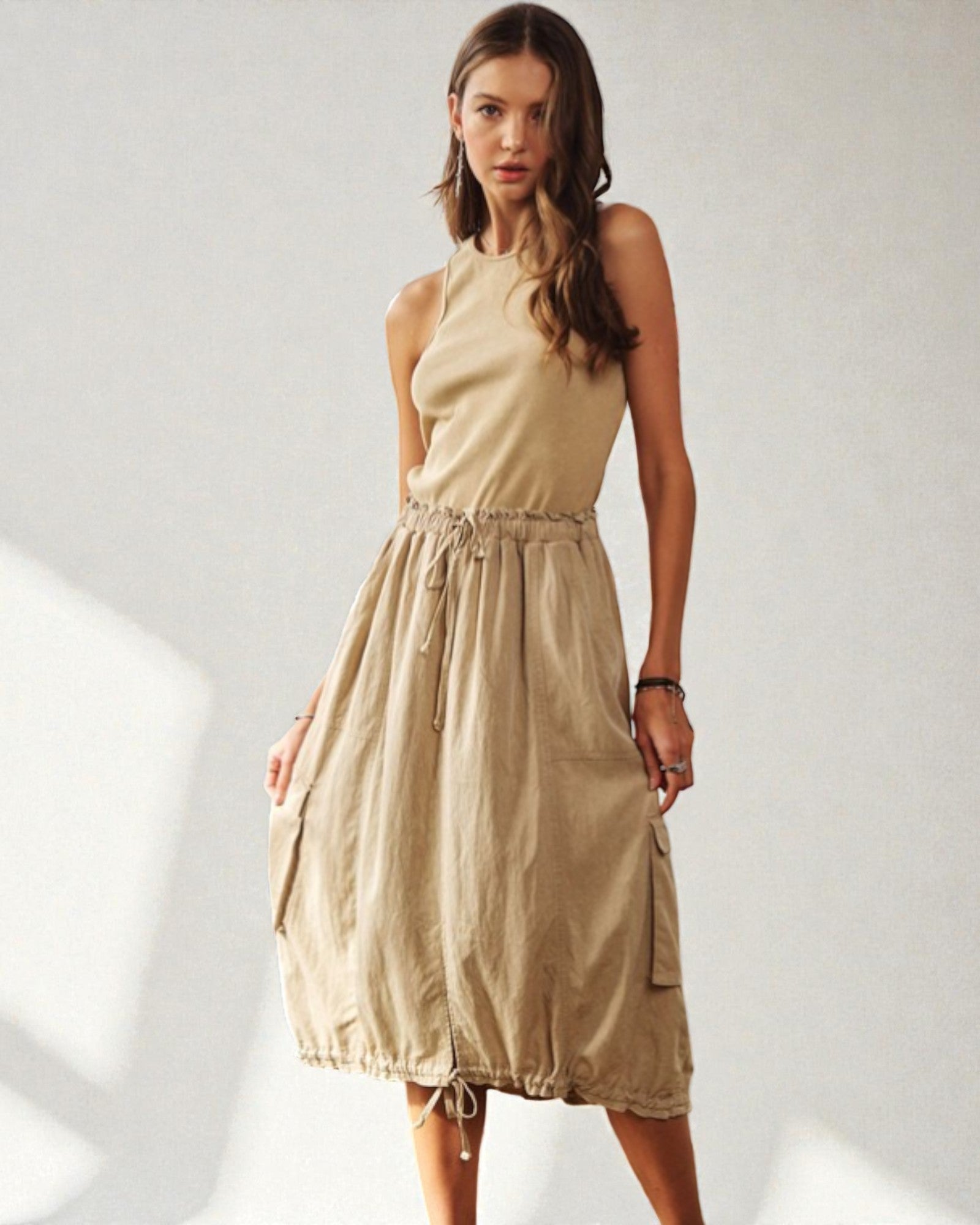 Woman wearing a beige sleeveless dress on a white background