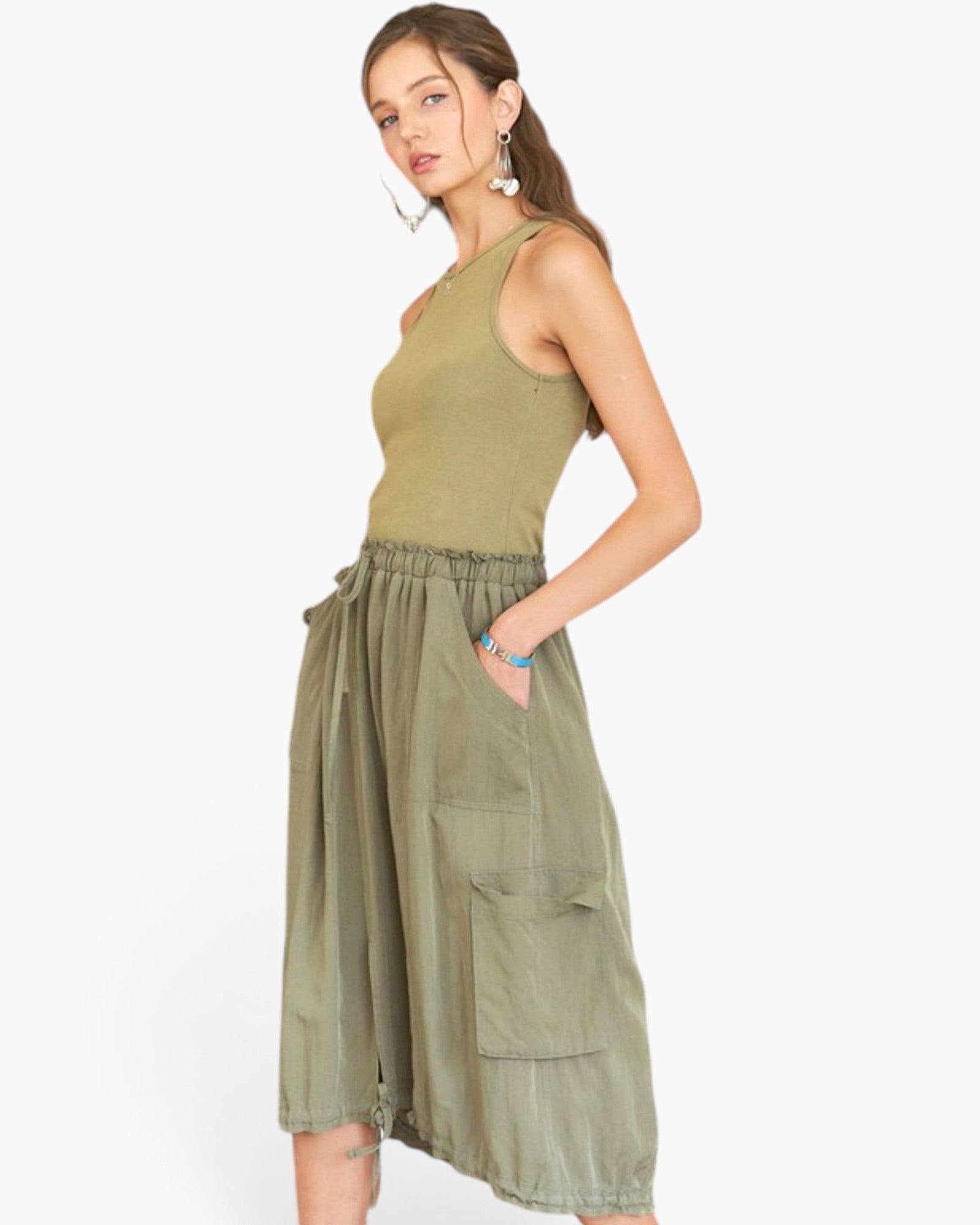 A woman modeling a sleeveless olive green top and matching olive green high-waisted cargo skirt against a plain white background.