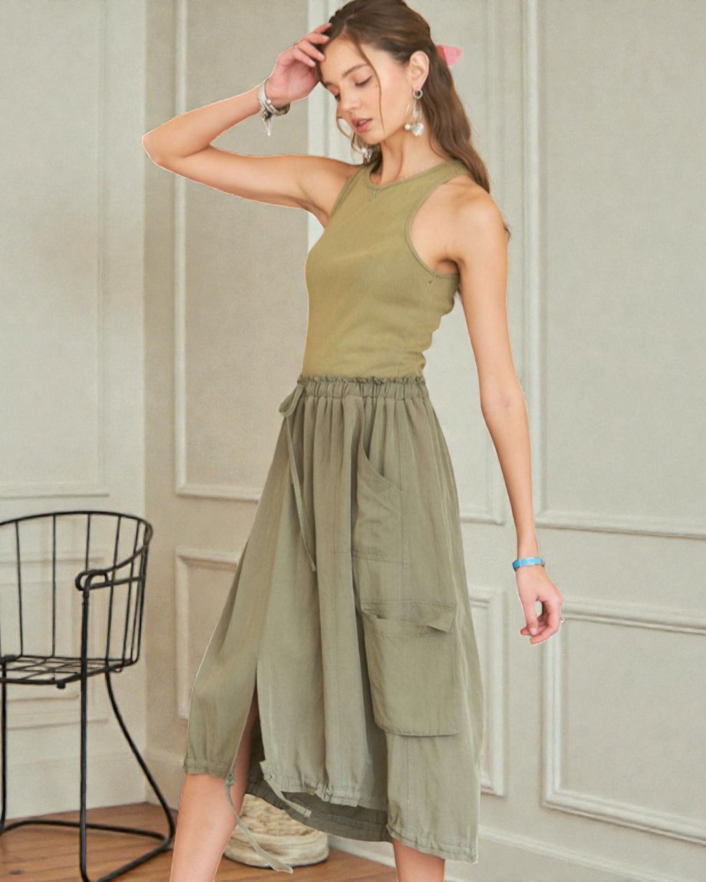 Woman wearing a green sleeveless top and skirt in an indoor setting.