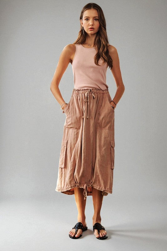 Woman wearing a pink sleeveless top and cargo skirt on a gray background