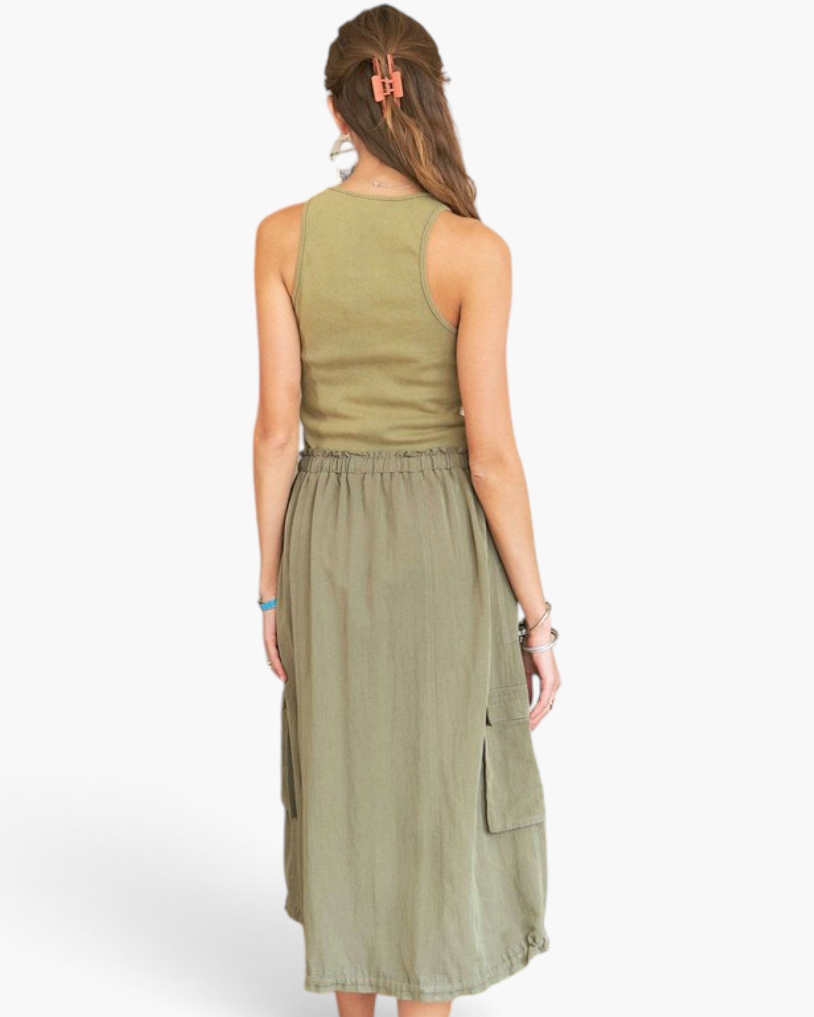 A woman shown from the back wearing a sleeveless olive green top and matching olive green midi skirt with side cargo pockets, against a plain light gray studio background.