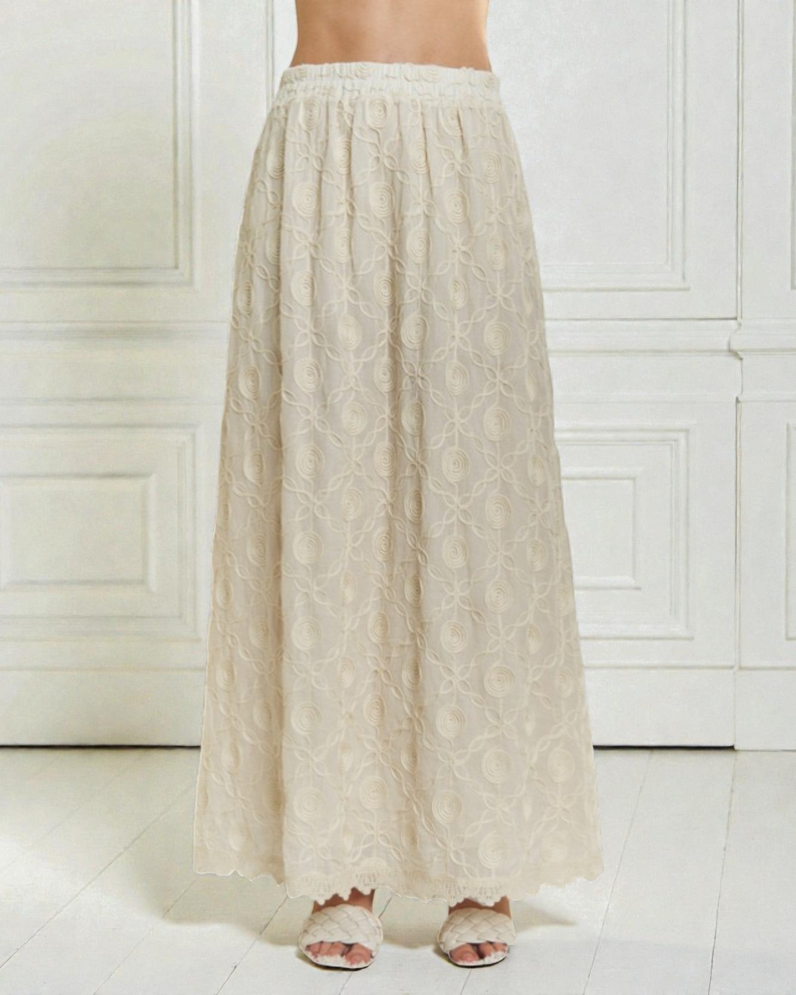 Beige lace skirt worn by a person on a white background