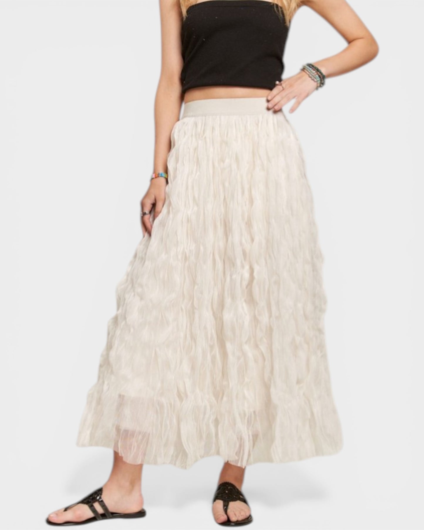 Person wearing a black top and beige skirt on a white background