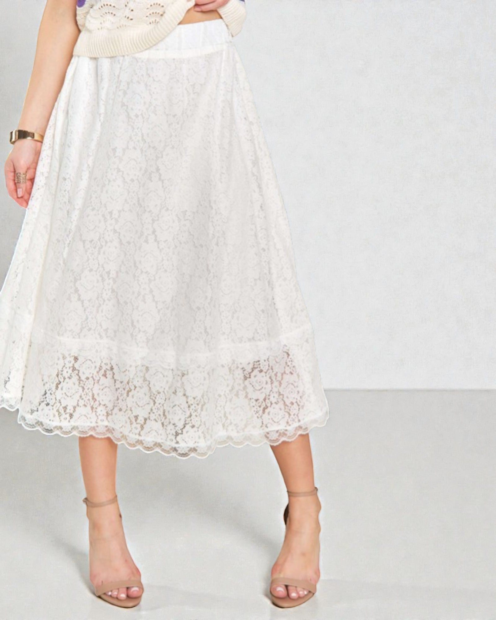 White lace skirt worn by a person on a plain background