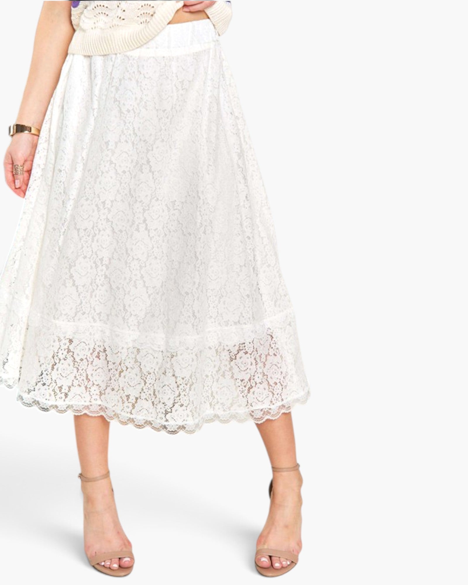 A white lace midi skirt with a scalloped hem, shown on a model wearing beige heeled sandals against a light gray studio background.