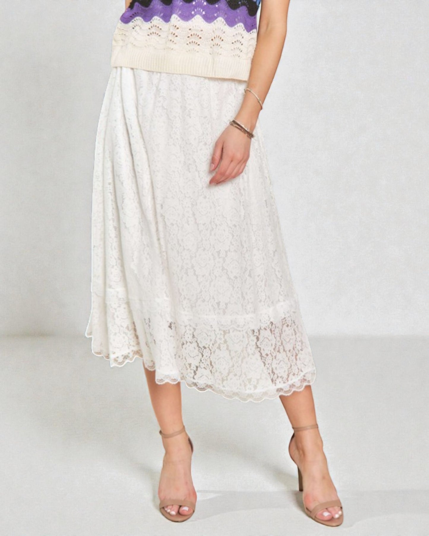 Person wearing a white lace skirt with a plain background
