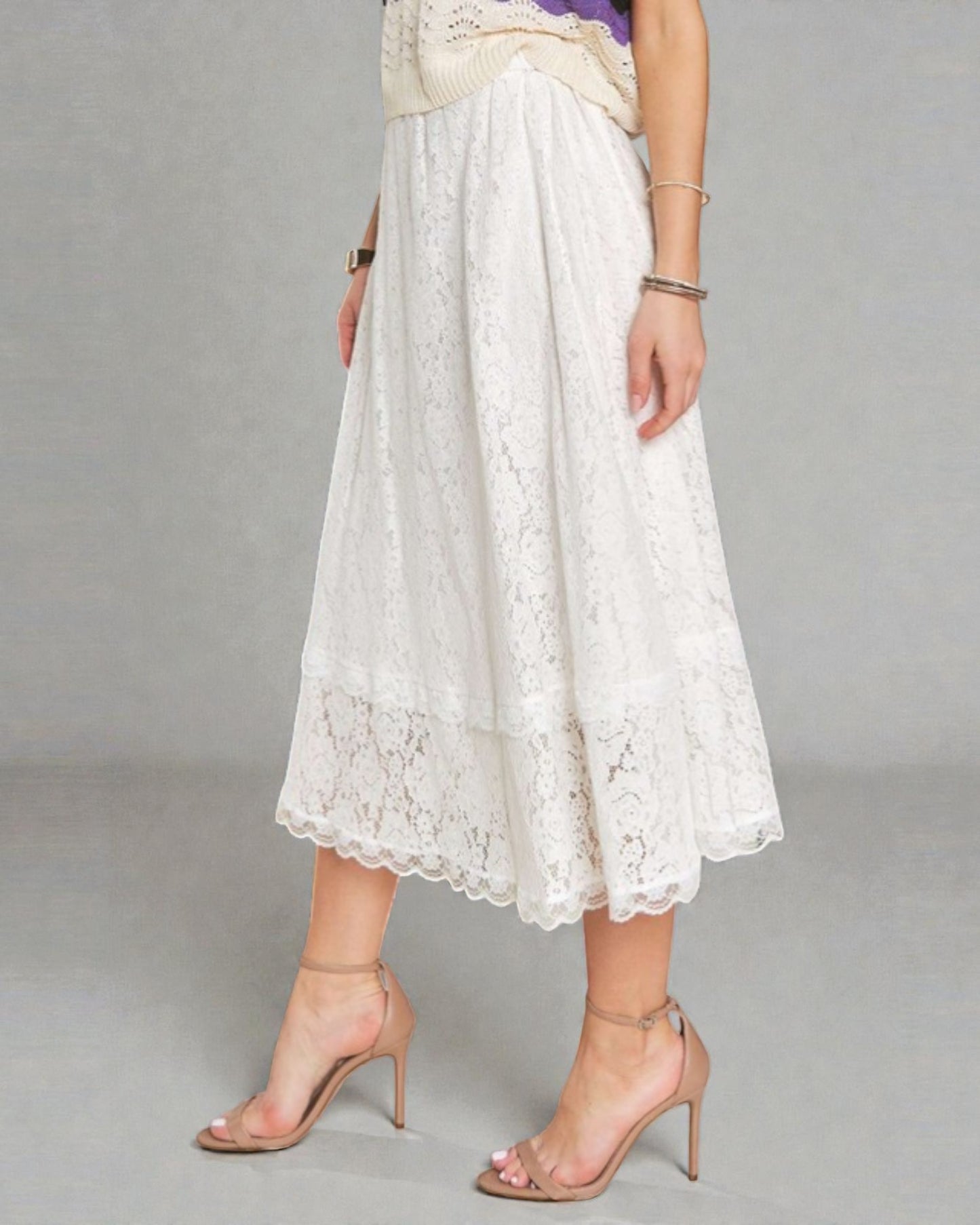 Person wearing a white lace skirt on a gray background