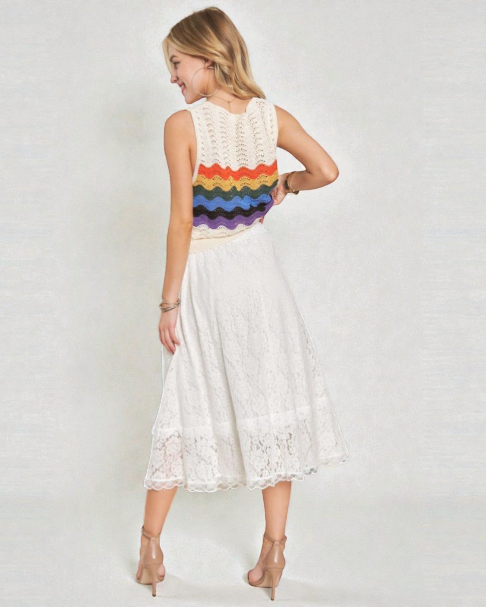Woman wearing a white lace dress with a colorful pattern on a plain background