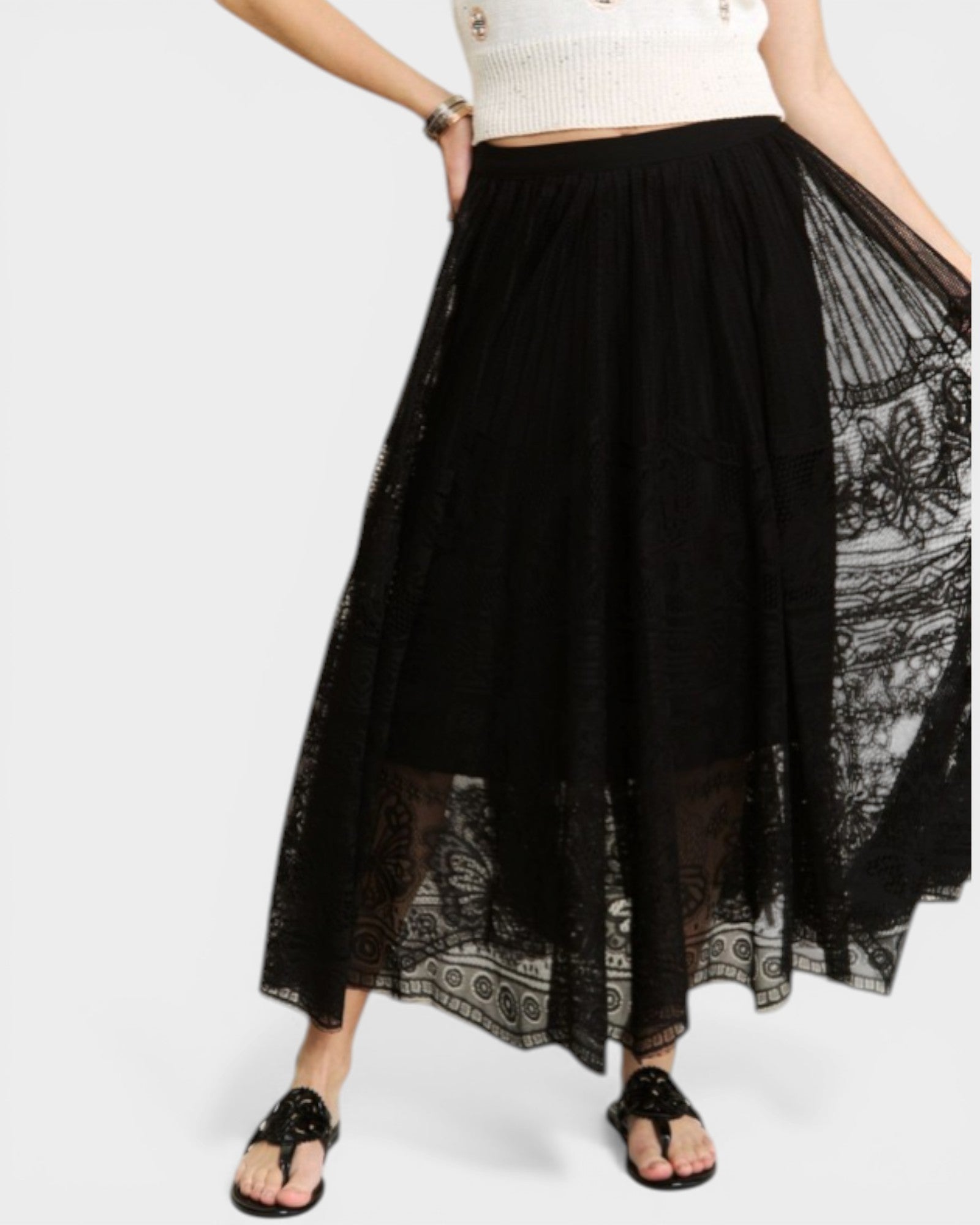 Black lace skirt with a white top and sandals on a white background