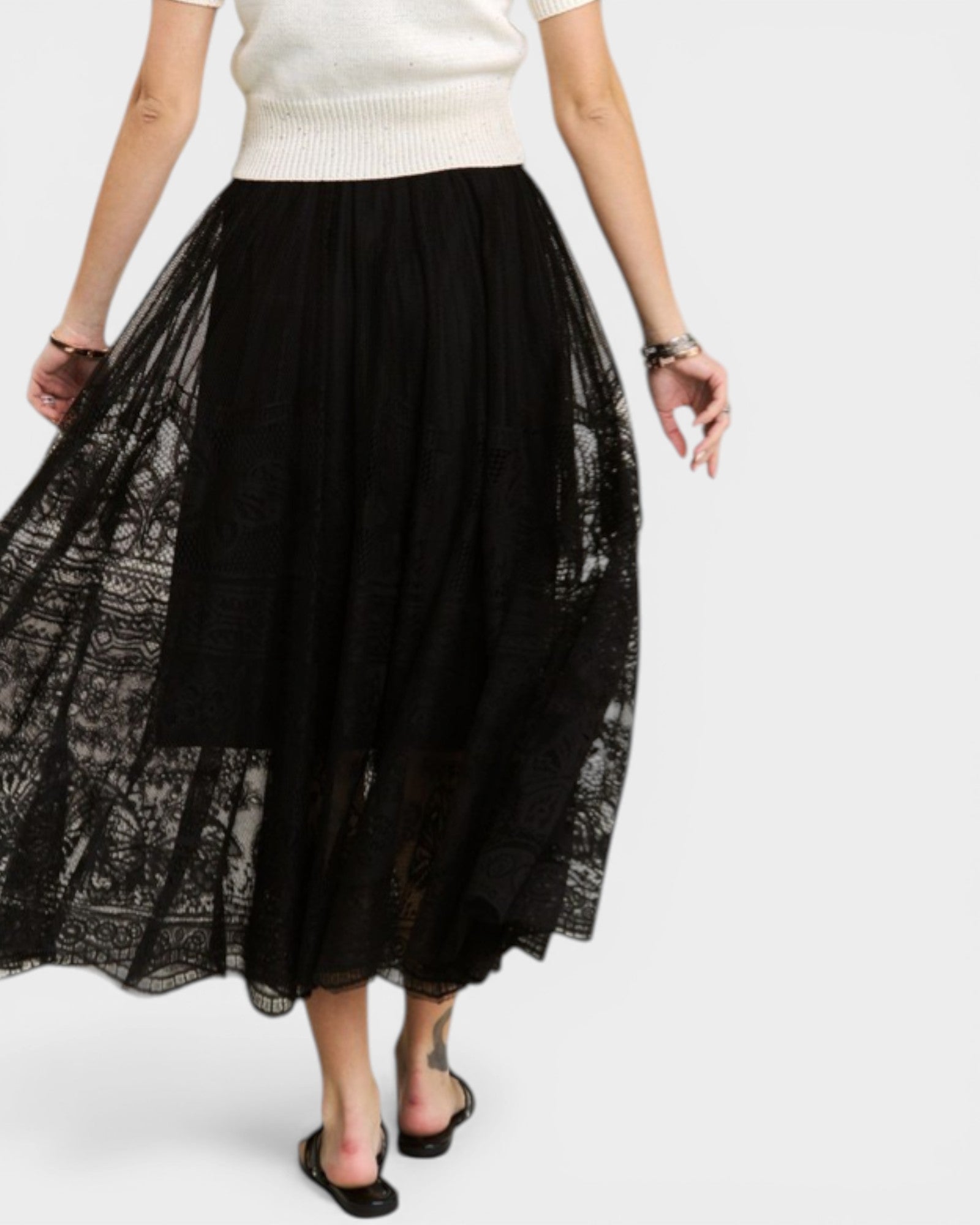 Person wearing a black lace skirt and white top on a white background