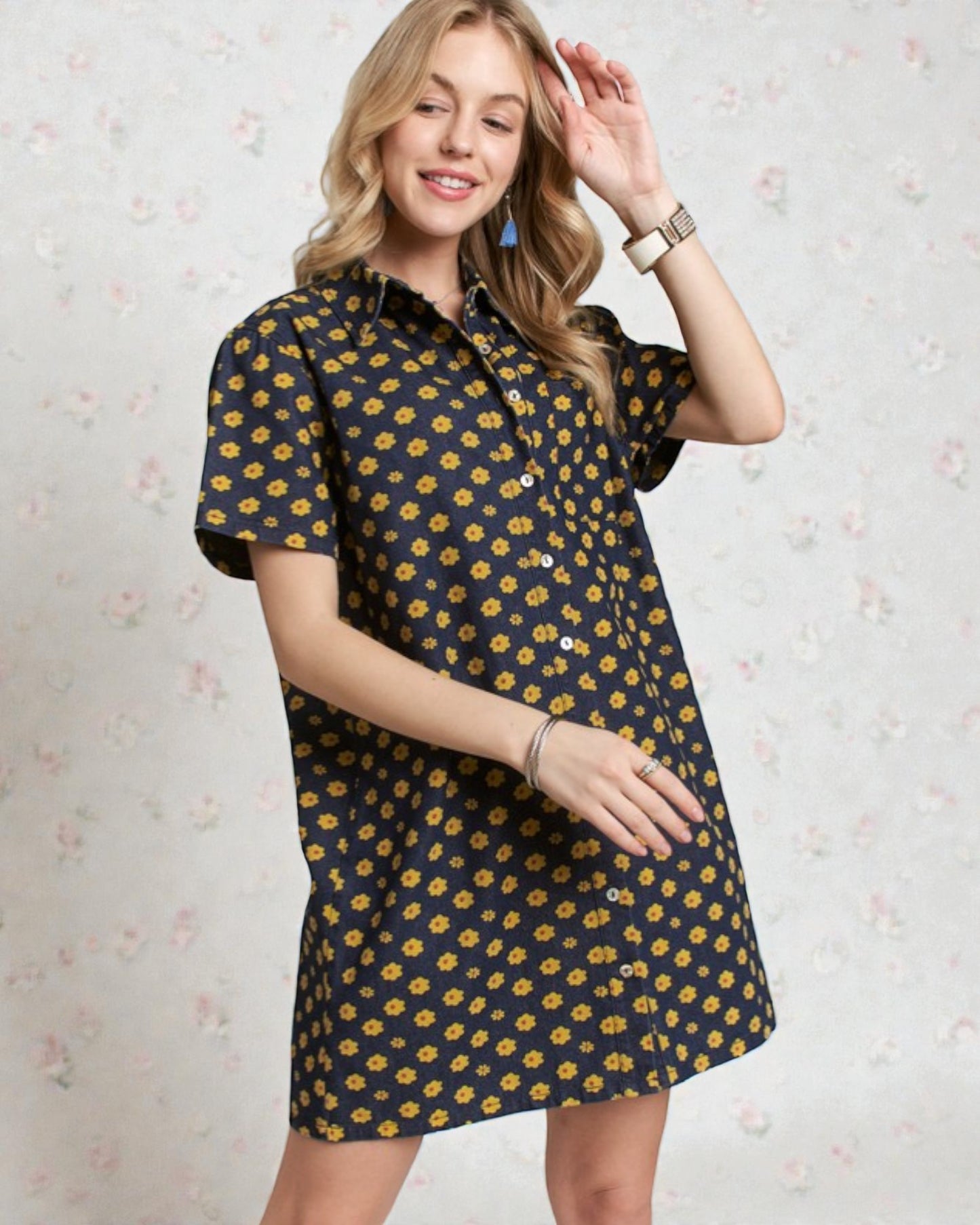 Woman wearing a navy dress with yellow floral pattern against a light floral background