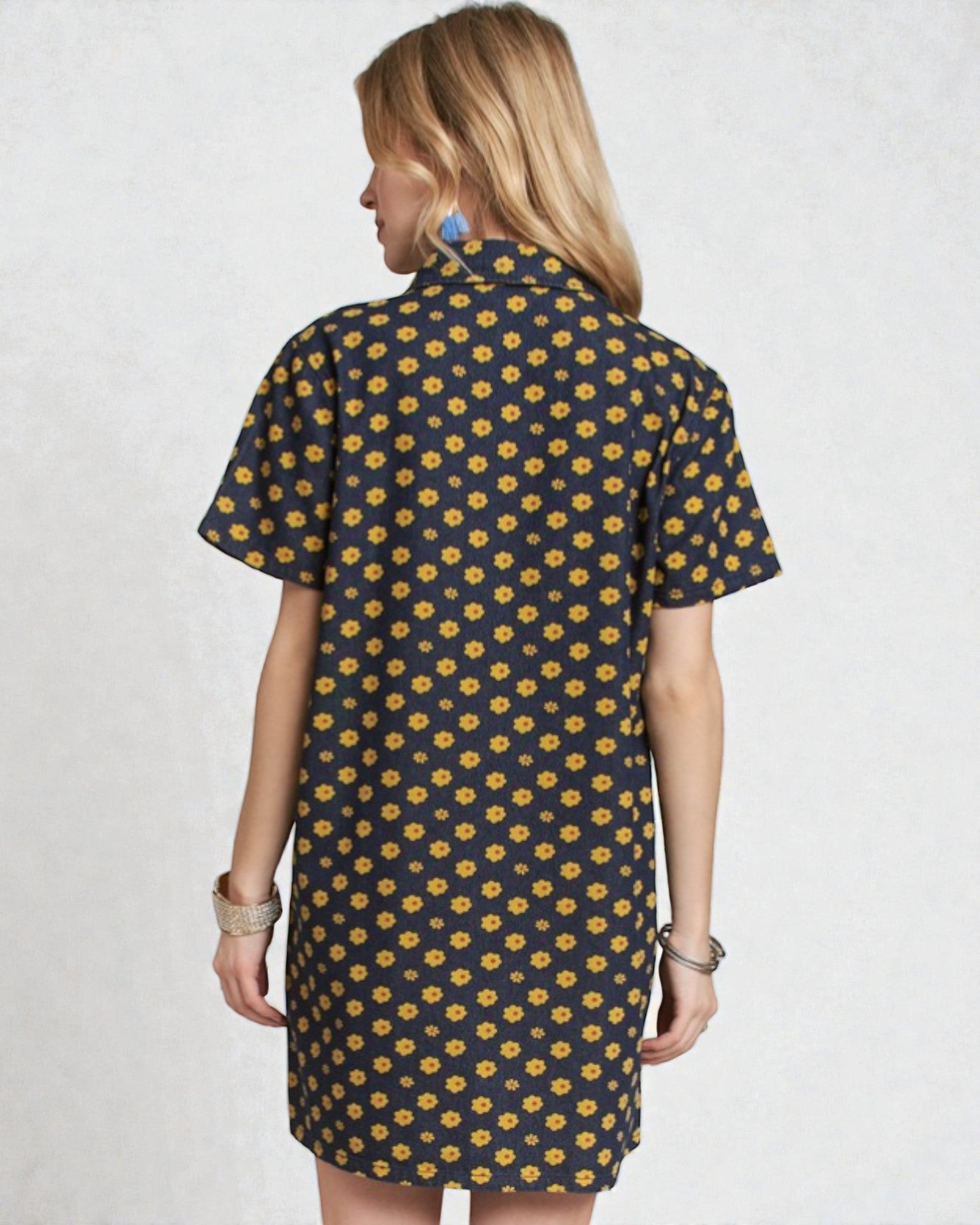 Woman wearing a black dress with yellow floral pattern on a white background