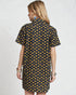 Woman wearing a black dress with yellow floral pattern on a white background