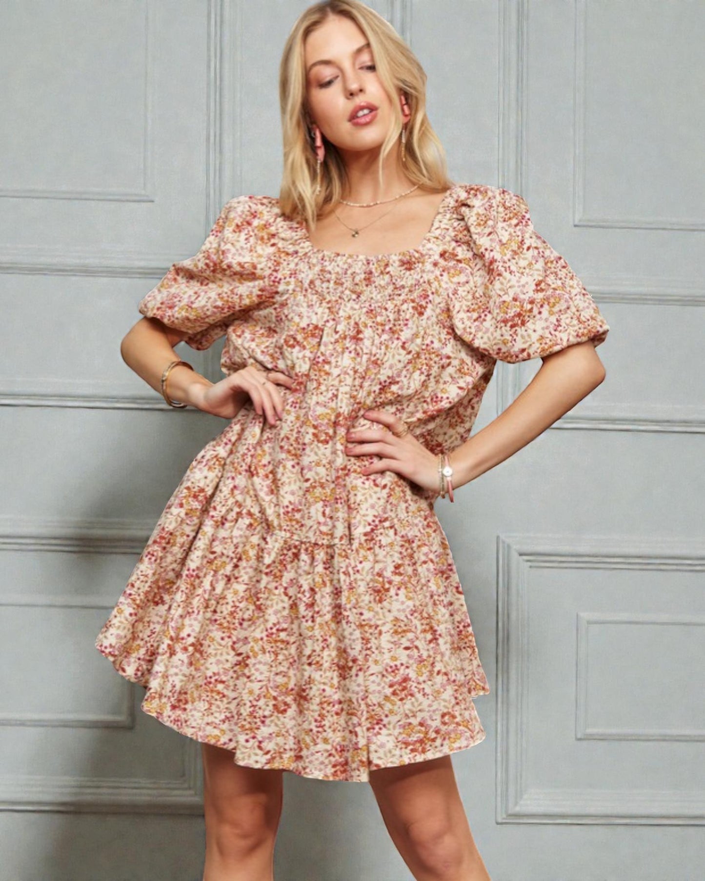 Woman wearing a floral dress against a gray paneled wall
