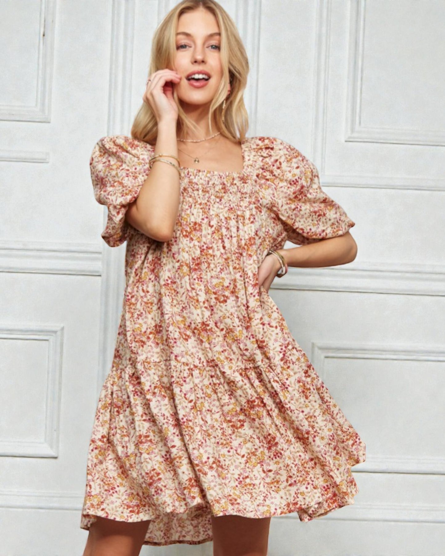 Woman wearing a floral dress against a white paneled wall