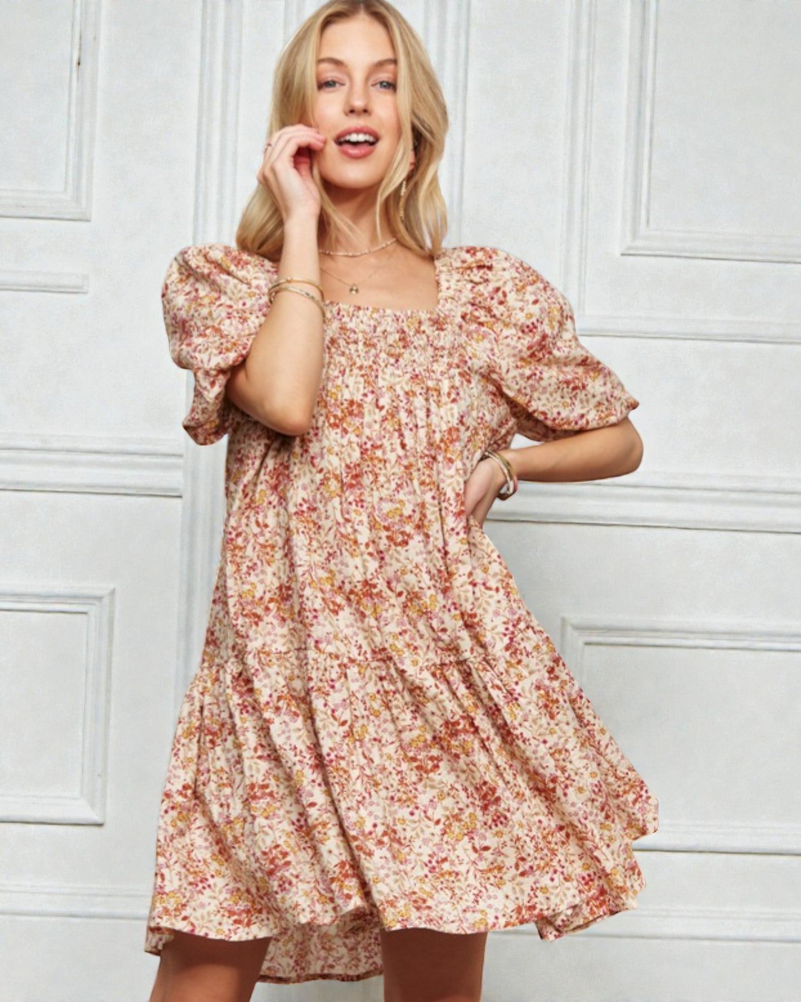 Woman wearing a floral dress against a white paneled wall