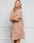 Woman wearing a floral dress against a white wall