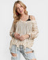 Woman wearing a beige oversized sweater and ripped jeans on a white background