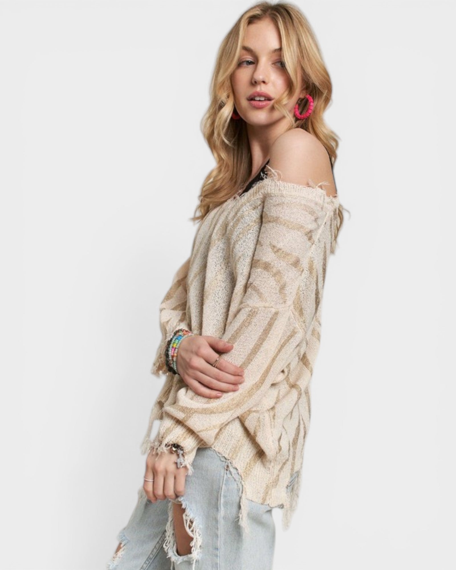 Woman wearing a beige off-shoulder sweater with a white background